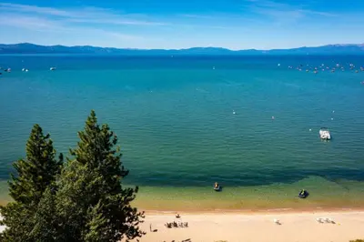 a large body of water with people on a beach at Lakeland Studio - Walk to Casinos, Restaurants And Gondola in South Lake Tahoe
