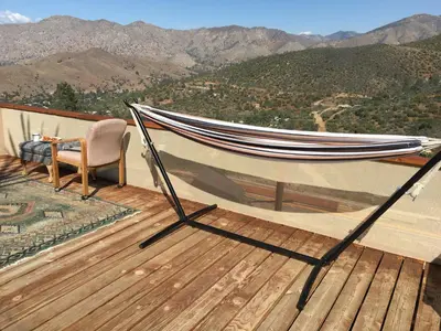 a hammock on a deck with a view of mountains at Big Glamping Teepee in Bodfish