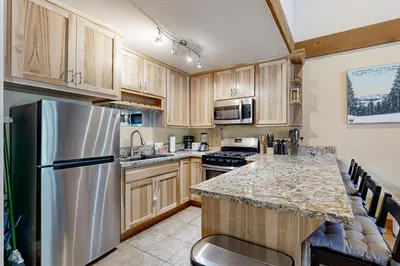 a kitchen with wooden cabinets and a stainless steel refrigerator at The Cozy Condo in Kingswood Estates
