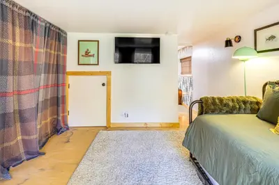 a bedroom with a bed and a tv on the wall at Walk to Golf, Lake Twain Harte Cabin with Fireplace in Twain Harte