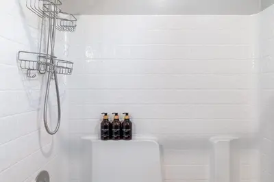 a white bathroom with bottles on the back of a tub at Spacious 4BR Home With BBQ, Near Sequoia & Fresno in Hanford