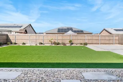 a backyard with a fence and a green lawn at Spacious 4BR Home With BBQ, Near Sequoia & Fresno in Hanford