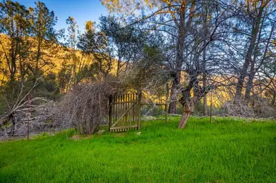 a gate in a grassy field with a tree at Sierra Vista Lookout Lodge for 8 people with Hot tub, deck and trail to waterfalls in North Fork
