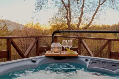 a jacuzzi tub with two wine glasses and a table at 10-acre Forest Villa, 20 miles from Yosemite South in Oakhurst