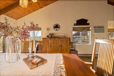 a dining room with a table with a vase on it at 10-acre Forest Villa, 20 miles from Yosemite South in Oakhurst