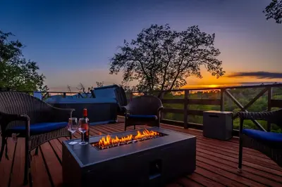 a fire pit on a deck with a sunset in the background at 10-acre Forest Villa, 20 miles from Yosemite South in Oakhurst