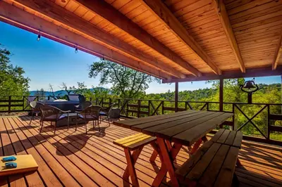a wooden deck with a table and a picnic table at 10-acre Forest Villa, Single Floor, Hot tub, Patio in Oakhurst