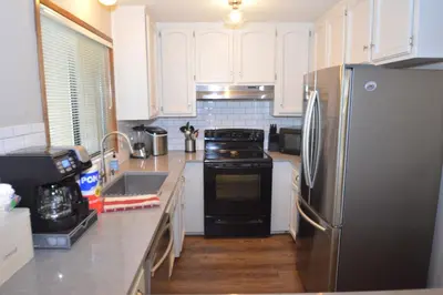 a kitchen with white cabinets and a black refrigerator at SunRidge at Willow Cove Free Night Special in Bass Lake