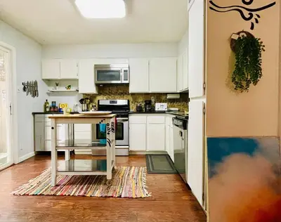 a kitchen with white cabinets and a table in it at Artist's Condo with 2 Bedroom & Arcade in Sacramento
