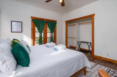 a bedroom with a large white bed with green pillows at Cedar Creek Lodge with POOL/hot tub/sleeps 24 in Oakhurst