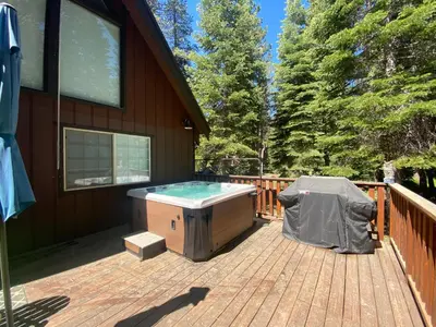 a hot tub on a deck next to a house at Donner Gem by Tahoe Getaways - Beautifully Updated, Hot Tub, Pet Friendly in Truckee