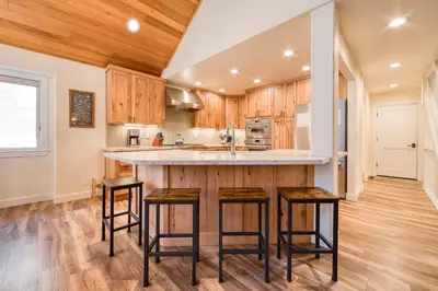 a kitchen with wooden cabinets and a large island with bar stools at Venture in Tahoe Donner by Tahoe Getaways - 4 BR W Hot Tub, Pool Table, Great for Kids! in Truckee