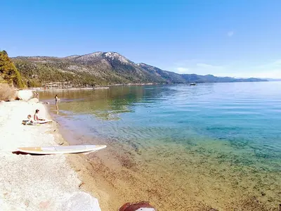 a surfboard laying on a beach next to the water at Experience the Beauty of Tahoe from Your Zephyr Cove Retreat! #2 in Zephyr Cove