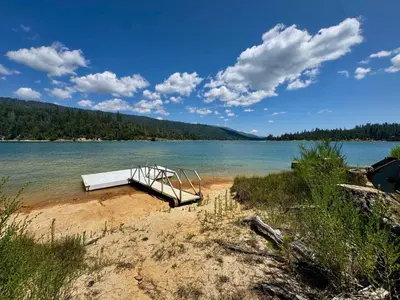 a dock on a beach next to a body of water at Wishon Lake Front, Price Reduced, 3day Min in Bass Lake