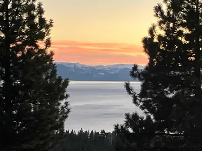 a view of a lake from between two trees at Lake Tahoe Vacation Rental Fireplace and Balcony in Incline Village