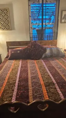 a bed with a blanket on it with a window at The Secret Hideaway in Oakhurst