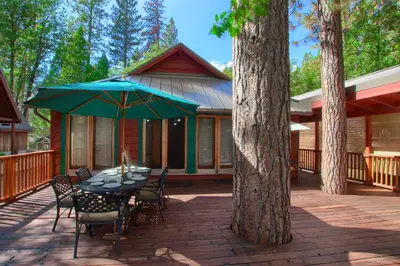 a table with chairs and an umbrella on a patio at Black Oak Lodge at The Redwoods in Wawona