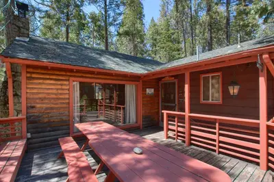 a log cabin with a picnic table on a deck at Shangri la-de-da at The Redwoods in Wawona