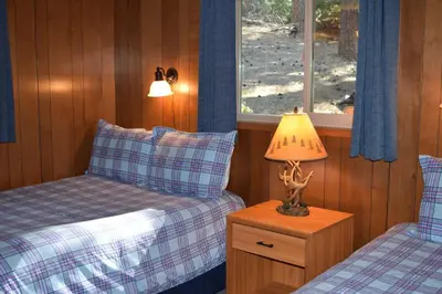 a bedroom with two beds and a lamp on a night stand at Sequoia House at The Redwoods in Wawona