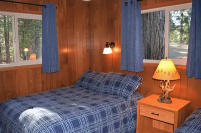 a bedroom with a bed and a lamp on a night stand at Sequoia House at The Redwoods in Wawona