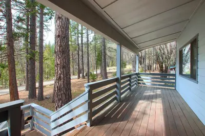 a wrap around porch with a view of the woods at Cabin Among the Firs in Wawona