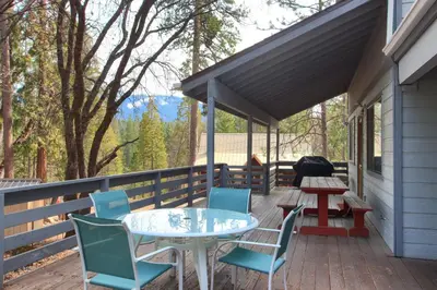 a patio with a table and chairs on a deck at Cabin Among the Firs in Wawona