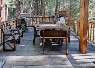 a wooden deck with a table and chairs on a cabin at Cabin Twelve in Wawona