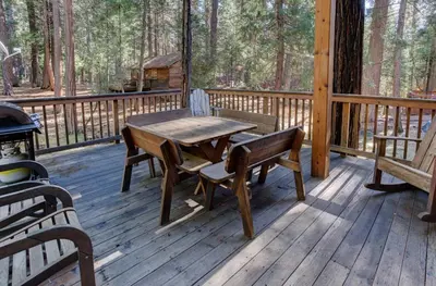 a wooden deck with a wooden table and benches at Cabin Twelve in Wawona