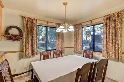 a dining room with a table and chairs and windows at Cabin Twelve in Wawona