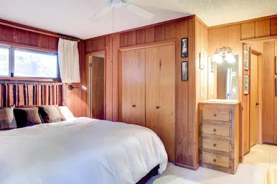 a bedroom with a white bed and a wooden wall at Star Gazers in Wawona