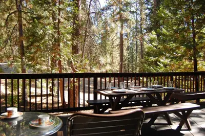 a wooden table and chairs on a deck with trees at Star Gazers in Wawona