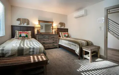 a bedroom with two beds and a dresser and a mirror at Hilltop Haven in Wawona