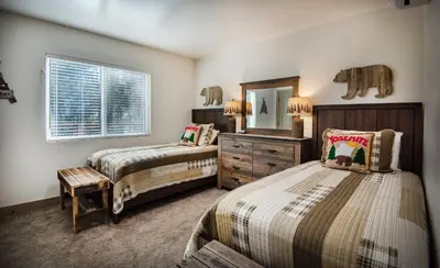 a bedroom with two beds and a dresser and a mirror at Hilltop Haven in Wawona