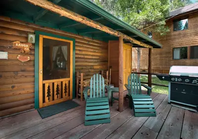 a cabin with chairs and a grill on a deck at Chipmunk Hollow in Wawona