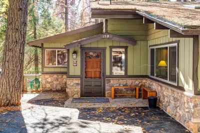 a small green house with a porch and a door at The Legacy in Wawona