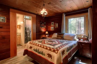 a bedroom with a bed in a room with wooden walls at Chipmunks Holiday in Wawona