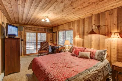 a bedroom with a bed and a desk and a television at Tyler's Timber Lodge in Wawona