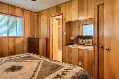 a bedroom with wooden walls and a bed and a window at New Beginnings at The Redwoods Cabin in Wawona