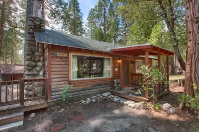 a log cabin in the woods with a porch at Le Fawn in Wawona