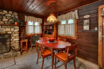 a dining room with a table and chairs and a fireplace at Le Fawn in Wawona