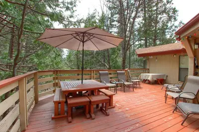 a wooden deck with a picnic table and an umbrella at Pohono Pines in Wawona