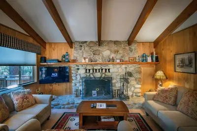 a living room with a stone fireplace in a house at Yosemite Retreat in the Meadows in Wawona