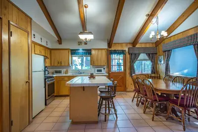 a kitchen with wooden cabinets and a table and chairs at Yosemite Retreat in the Meadows in Wawona
