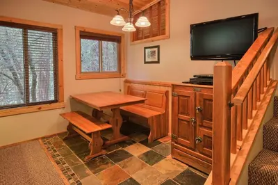 a dining room with a table and a flat screen tv at The Tree House in Wawona