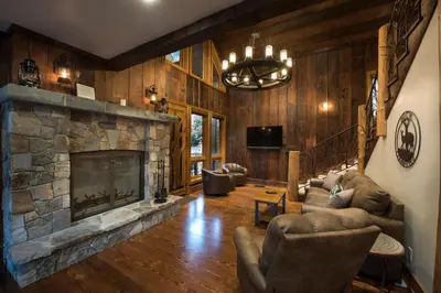 a living room with a stone fireplace in a house at Rustic Retreat in Wawona