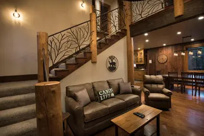 a living room with a couch and a staircase at Rustic Retreat in Wawona