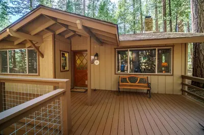 a small house with a deck in the woods at We-Dunn-It in Wawona