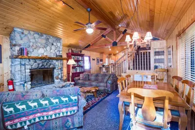 a living room with a couch a table and a fireplace at River Refuge in Wawona