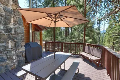 a wooden deck with a bench and an umbrella at Bradley's Cabin in Wawona