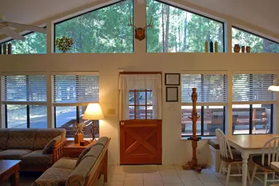 a living room with a bunch of windows and a table at Big Cedar in Wawona